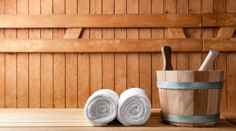 Secchio da sauna con due asciugamani arrotolati