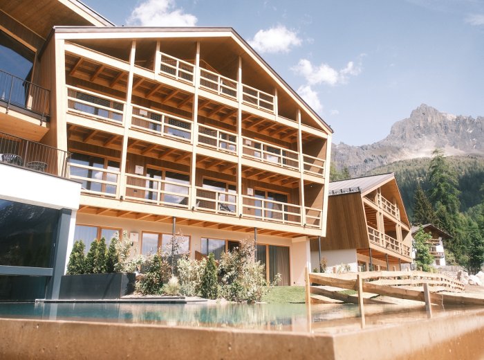 Moderno complesso alberghiero con piscina esterna e panorama montano.