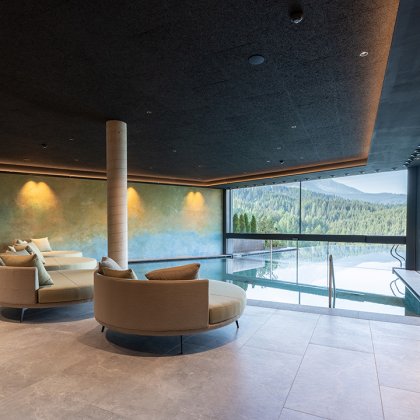 Piscina interna moderna con divani rotondi e grandi finestre con vista sulle montagne