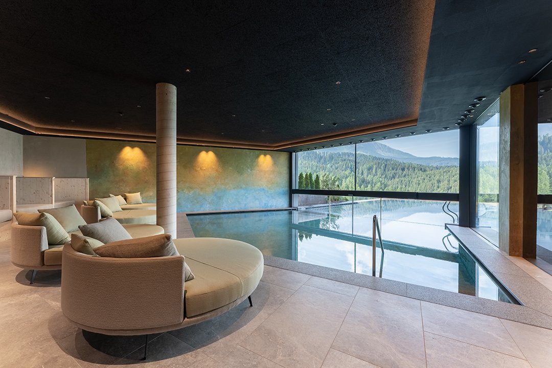 Piscina interna moderna con sedute rotonde a sinistra e finestre panoramiche con vista montagna a destra