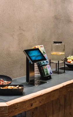Tavolo rustico con ciotole di noci, dispenser d'acqua al limone e ciotola di frutta accanto a fiori secchi