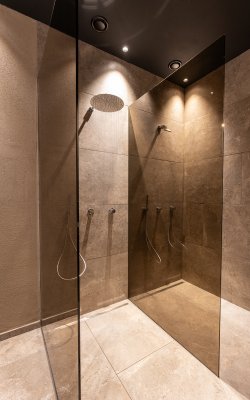 Modern walk-in shower with glass partition and brown tiles