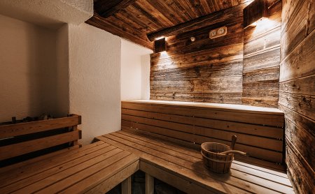 Sauna in Altholzoptik mit Eimer auf Holzbank