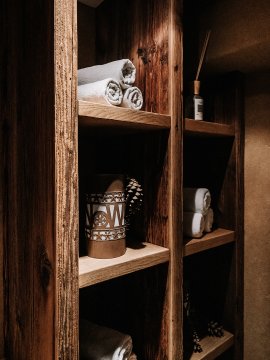 Scaffale in legno con asciugamani, decorazioni e profumo