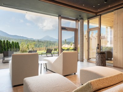 Interno moderno con poltrone comode e vista su terrazza e montagne attraverso grandi finestre