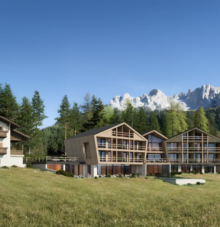 Das Family Nature Resort Ortnerhof in den Dolomiten zeigt moderne Chaletgebäude und ein traditionelles Haupthaus, eingebettet in eine sonnige Alpenlandschaft mit Wäldern und Berggipfeln – ideal für Natururlaub und Familienferien.