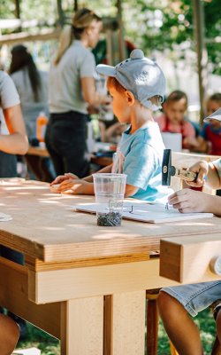 Bambini che lavorano all’aperto a un tavolo con attrezzi