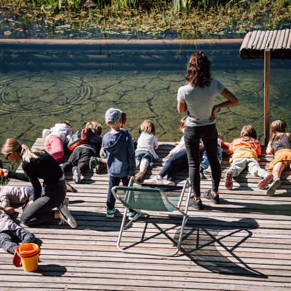 Kindergruppe beobachtet Natur am Holzsteg mit Teich