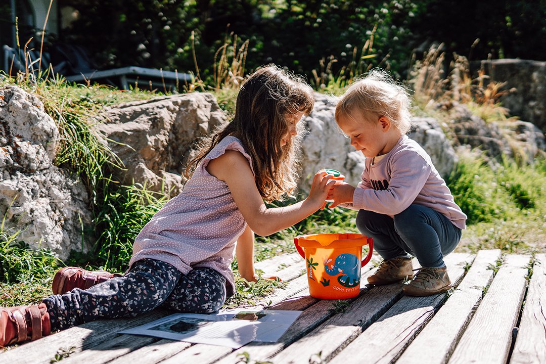 Zwei Kinder spielen am Steg mit orangem Eimer