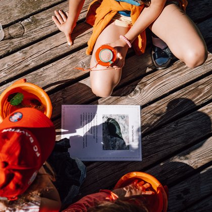 Bambini osservano con lente sul molo di legno