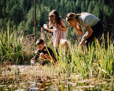 Donna e bambini osservano l’acqua con bicchieri