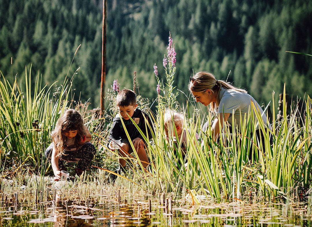 Frau und Kinder schöpfen Wasser aus dem Teich