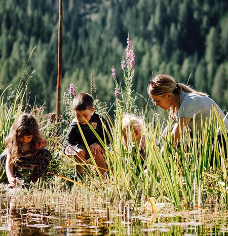 Frau und Kinder schöpfen Wasser aus dem Teich