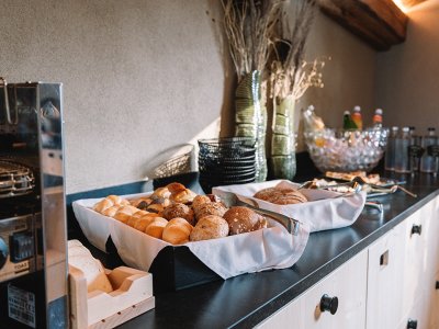 Frühstückstheke mit verschiedenen Brötchen, Toastbrot, Getränken und dekorativen Vasen auf schwarzer Arbeitsplatte