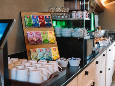 Theke mit Teebeuteln, Tassen und Kaffeemaschine in einem Café