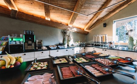 Buffet mit verschiedenen Aufschnitt- und Käseplatten in einer rustikalen Küche mit Holzbalkendecke