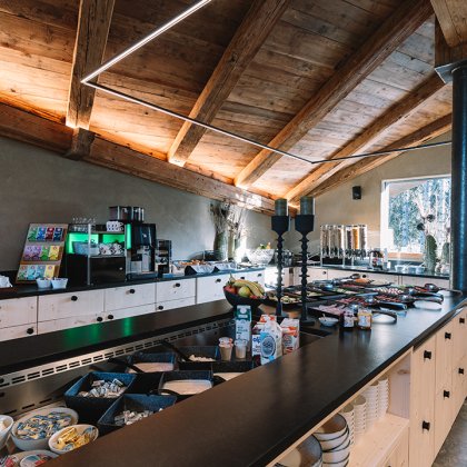 Buffet mit Frühstückszutaten in einem Raum mit Holzdecke und großem Fenster