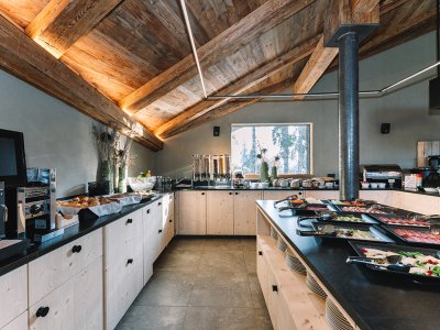 Buffet mit verschiedenen Speisen in einer rustikalen Küche mit Holzdecke und Fenster
