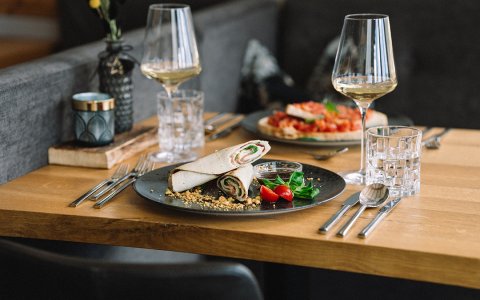 Teller mit Röllchen, Kirschtomaten, Salat und zwei Gläsern Weißwein