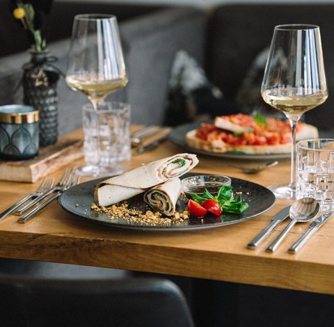 Teller mit Röllchen, Kirschtomaten, Salat und zwei Gläsern Weißwein
