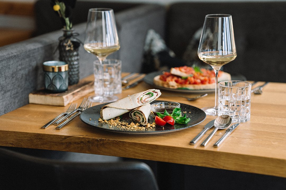 Teller mit Röllchen, Kirschtomaten, Salat und zwei Gläsern Weißwein