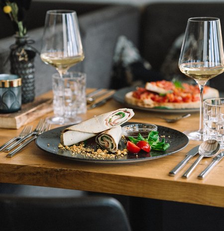 Teller mit Röllchen, Kirschtomaten, Salat und zwei Gläsern Weißwein