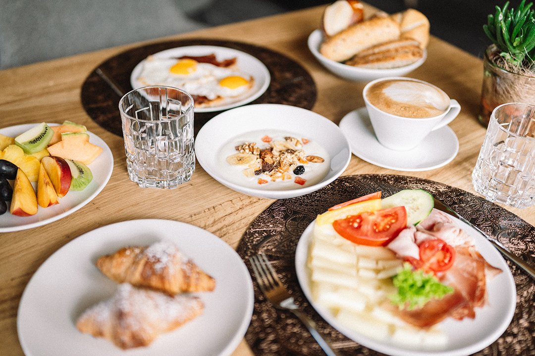 Frühstückstisch mit Croissants, Obst, Eiern, Aufschnitt, Käse und Kaffee