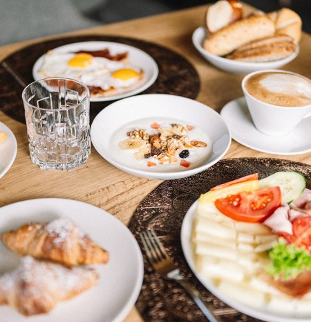 Frühstückstisch mit Croissants, Obst, Eiern, Aufschnitt, Käse und Kaffee