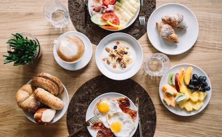 Tisch mit Eiern, Obst, Brot, Kaffee und Croissants zum Frühstück