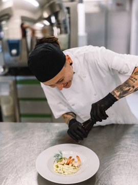 Koch würzt Pasta mit Garnelen in der Küche