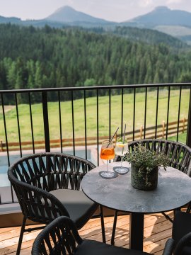 Runder Tisch mit zwei Getränken und Pflanze auf Balkon mit Bergblick