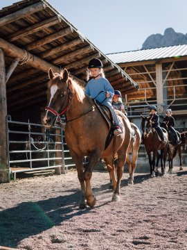 Bambini a cavallo durante lezione di equitazione al sole