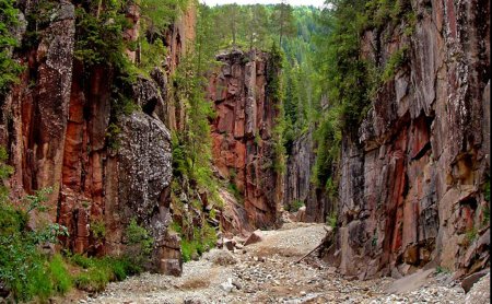 Rote Felsenschlucht mit Geröllbett und bewaldetem Rand