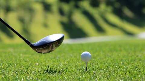 Golfschläger kurz vor dem Abschlag auf grüner Wiese