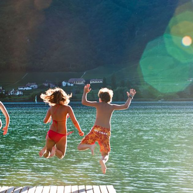 Bambini saltano felici da un molo in un lago limpido