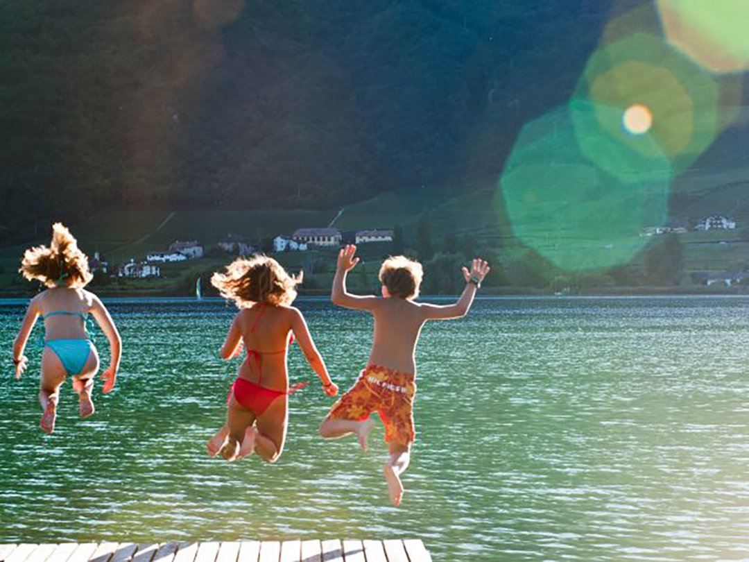Bambini saltano felici da un molo in un lago limpido