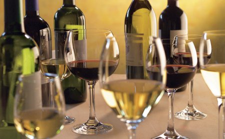 Gläser mit Weiß- und Rotwein vor Weinflaschen