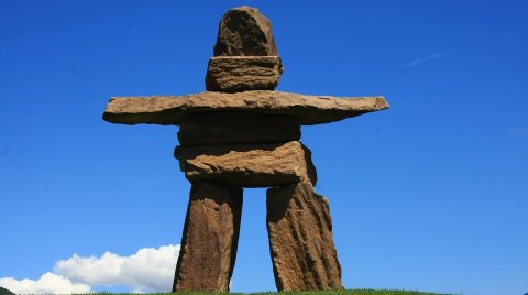 Steinfigur aus flachen Platten vor blauem Himmel