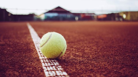 Tennisball liegt auf der Linie eines Sandplatzes