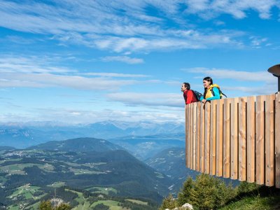 Wanderer lehnen an Holzplattform mit weitem Talblick