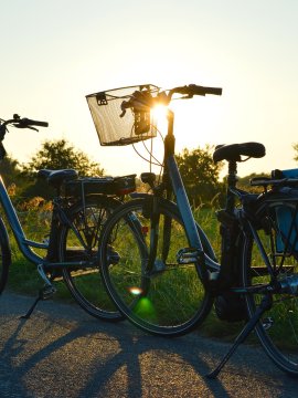 Zwei Tourenräder im Gegenlicht bei Sonnenuntergang auf Landstraße