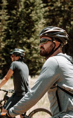 Zwei Radfahrer mit Helm im Wald, einer blickt zur Seite