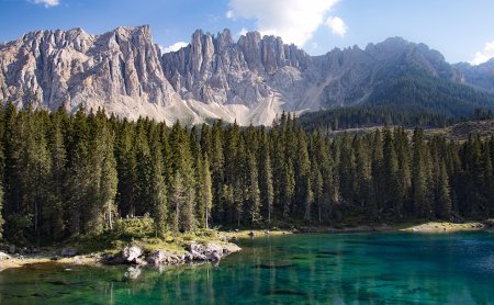 Klarer Bergsee mit Nadelwald und steilen Dolomitengipfeln