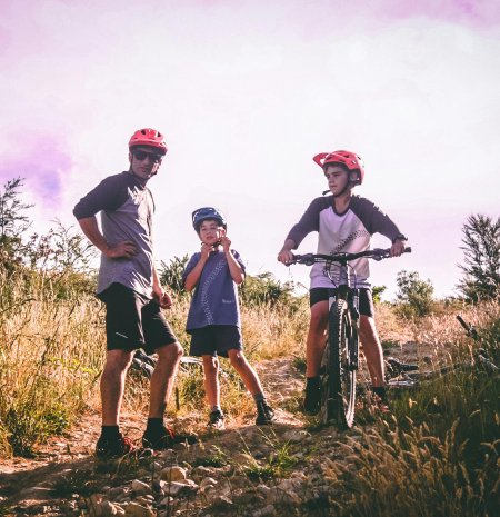 Familie mit Fahrrädern und Helmen auf steinigem Naturweg