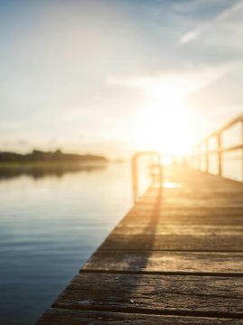 Molo in legno sul lago al tramonto con acqua tranquilla