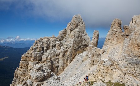 Wanderer auf steinigem Pfad zwischen schroffen Dolomitengipfeln