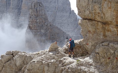 Wanderer mit Helm am Klettersteig zwischen steilen Felsen