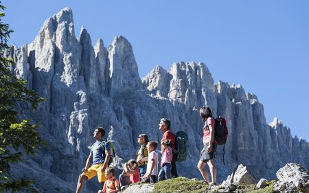 Family hiking in front of jagged mountain peaks