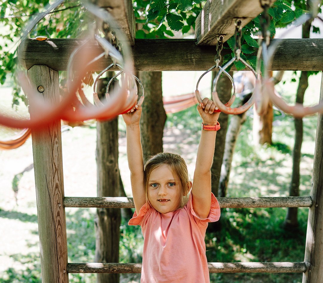 Bambina che si diverte sulle barre di arrampicata all’aperto nel parco giochi.