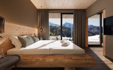 Modernes Schlafzimmer mit großem Holzbett, warmen Naturmaterialien und großen Fenstern, die einen Blick auf verschneite Berge und Wälder bieten.